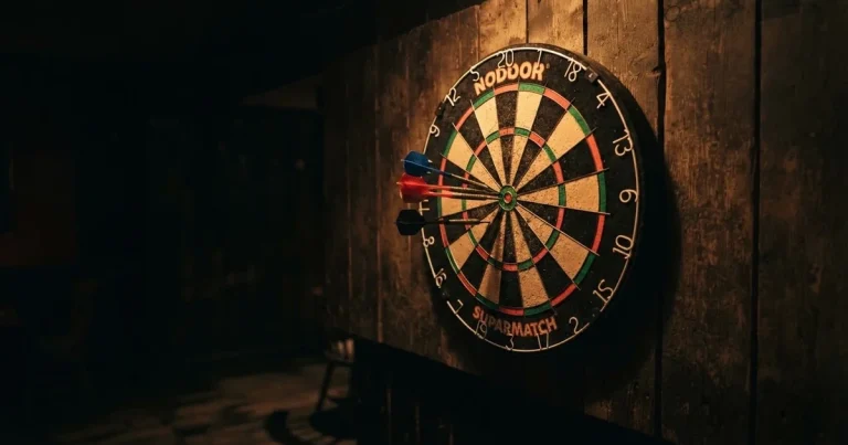 Eine Dartscheibe an einer Holzwand in einem schwach beleuchteten Raum, drei Pfeile stecken nahe der Mitte, warmes Licht von der Seite.
